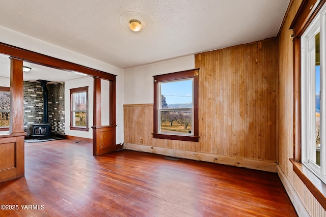 1555 W Tieton Rd, Tieton, WA 98947 - empty room featuring a wood stove, hardwood / wood-style floors, wooden walls, a textured ceiling, and baseboards