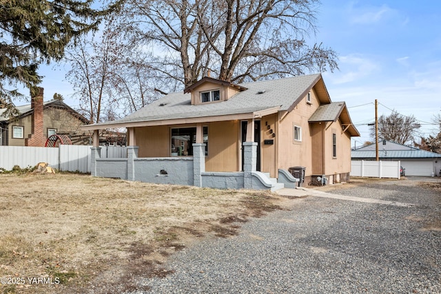 bungalow with a porch, fence, and a shingled roof