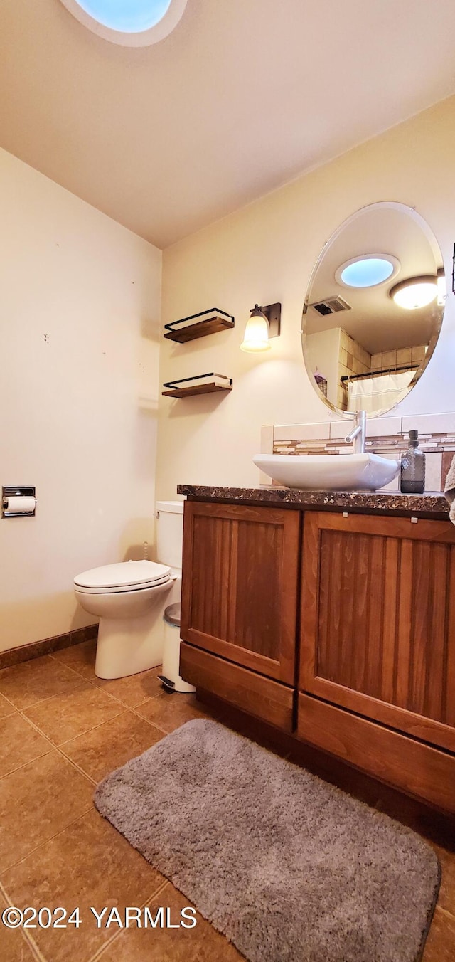 bathroom featuring baseboards, visible vents, toilet, tile patterned floors, and vanity