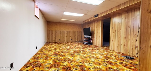 spare room featuring wooden walls and a drop ceiling