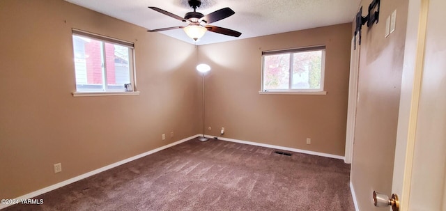 empty room with visible vents, baseboards, dark colored carpet, and a ceiling fan