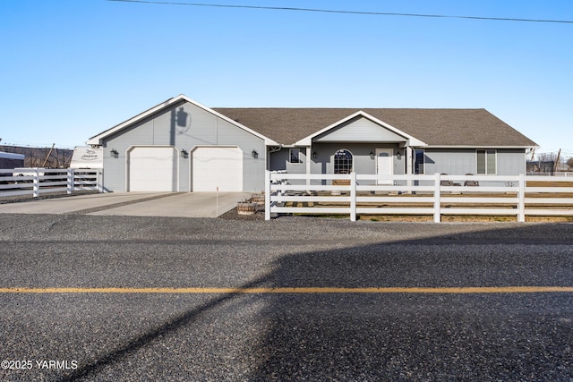 view of front of house with a fenced front yard, a garage, concrete driveway, and a shingled roof