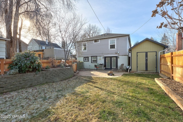 back of house featuring an outbuilding, a lawn, a patio area, a shed, and a fenced backyard