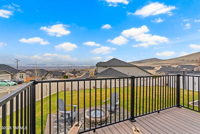 wooden terrace featuring a yard, a residential view, a fenced backyard, and an outdoor fire pit