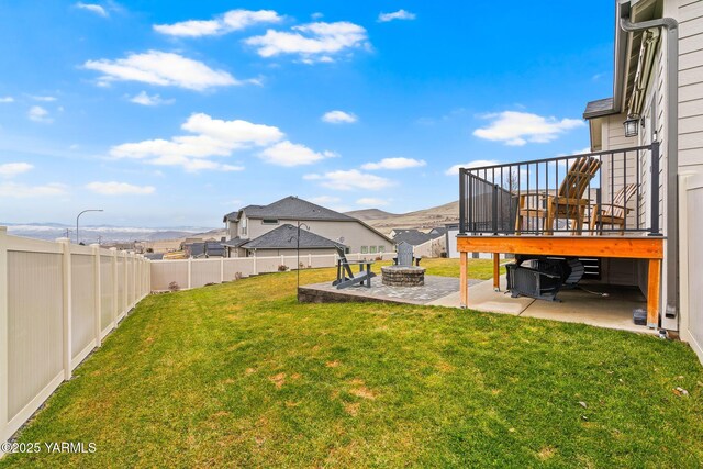 view of yard with a fenced backyard, a deck with mountain view, an outdoor fire pit, and a patio