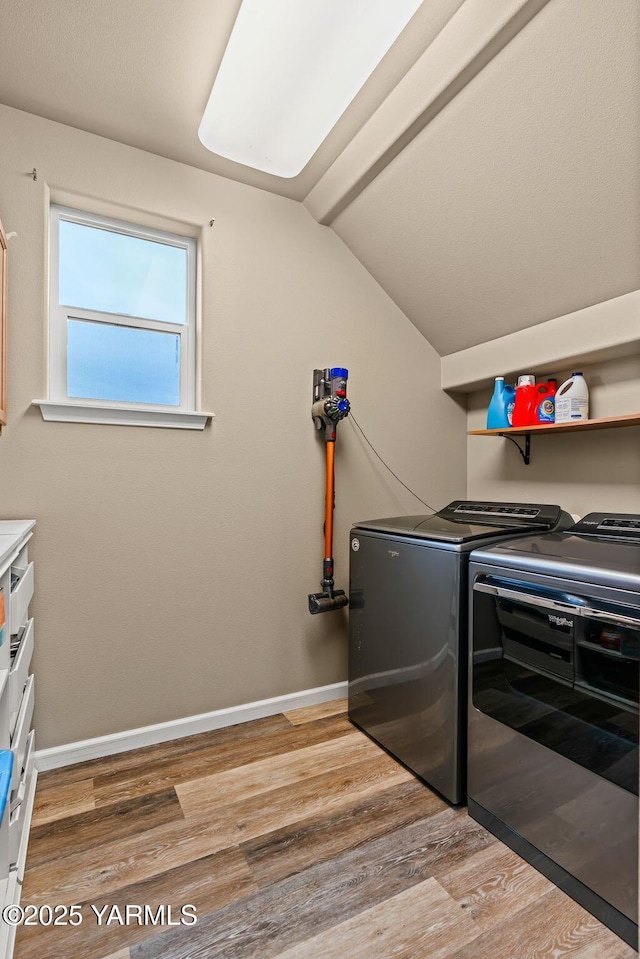 laundry area featuring washer and dryer, light wood-type flooring, cabinet space, and baseboards