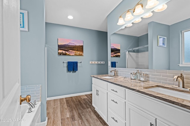 full bathroom with a shower with door, wood finished floors, backsplash, and a sink