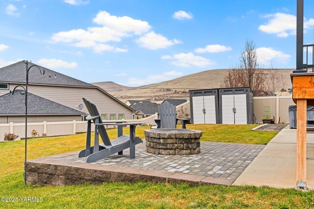 view of patio featuring fence, a shed, an outdoor fire pit, an outdoor structure, and a mountain view