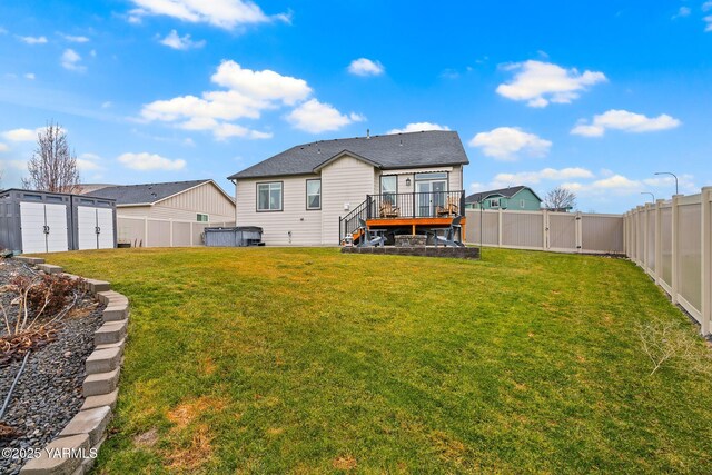 rear view of property with an outbuilding, a lawn, a deck, a gate, and a fenced backyard