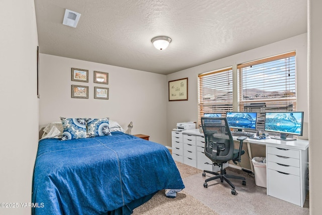 bedroom with visible vents, light carpet, and a textured ceiling