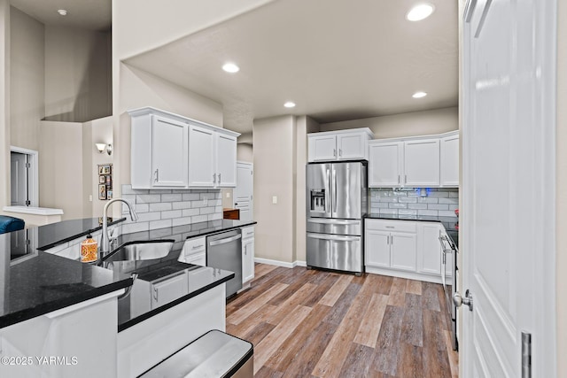 kitchen with white cabinetry, light wood finished floors, appliances with stainless steel finishes, and a sink