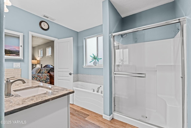 full bathroom featuring visible vents, a shower stall, a garden tub, wood finished floors, and ensuite bath