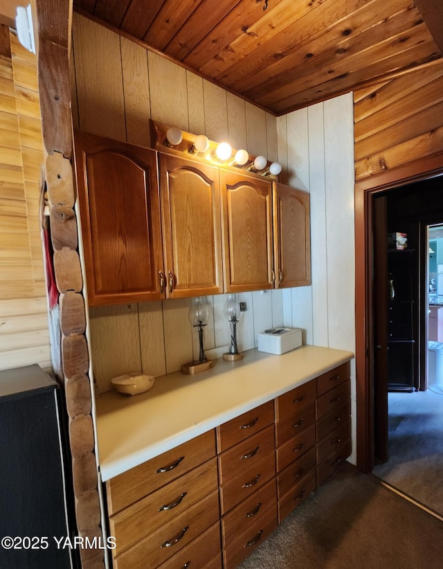 13520 Fisk Rd, Yakima, WA 98908 - kitchen with dark carpet, wooden ceiling, light countertops, brown cabinetry, and wooden walls
