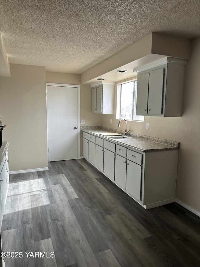 205 N 63rd Ave, Yakima, WA 98908 - kitchen with dark wood-type flooring, a sink, a textured ceiling, baseboards, and light countertops