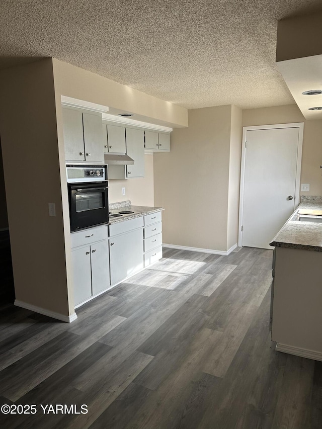 205 N 63rd Ave, Yakima, WA 98908 - kitchen with oven, dark wood-type flooring, a textured ceiling, cooktop, and baseboards