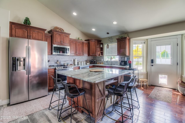 1008 S 90th Ave, Yakima, WA 98908 - kitchen featuring appliances with stainless steel finishes, a breakfast bar area, tasteful backsplash, a kitchen island, and light wood-style floors