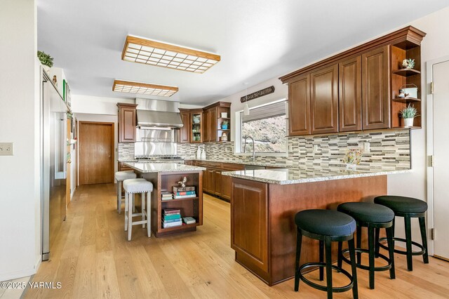 1011 N 42nd Pl, Yakima, WA 98908 - kitchen with open shelves, wall chimney range hood, a peninsula, and light wood finished floors