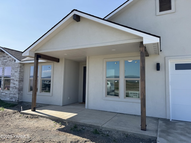 202 E Ian Ave, Ellensburg, WA 98926 - doorway to property with stucco siding, stone siding, a patio area, and a garage