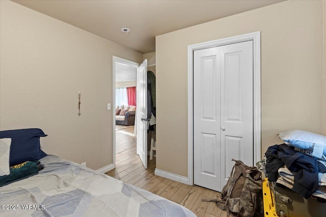 bedroom featuring light wood-style floors, a closet, and baseboards