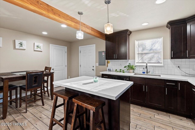 kitchen featuring decorative backsplash, a kitchen island, light countertops, pendant lighting, and a sink