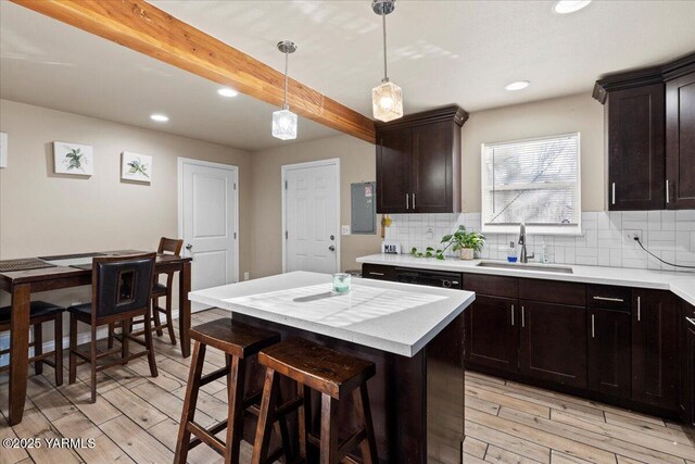 kitchen featuring decorative backsplash, a kitchen island, light countertops, pendant lighting, and a sink