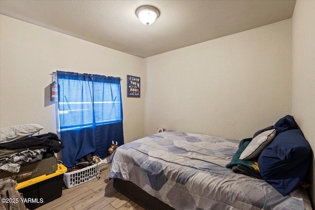 bedroom with a textured ceiling and wood finished floors