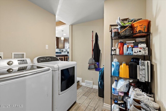 laundry area featuring laundry area, visible vents, baseboards, light wood finished floors, and washer and clothes dryer