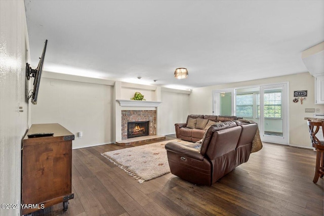 living room with a lit fireplace and dark wood-style flooring