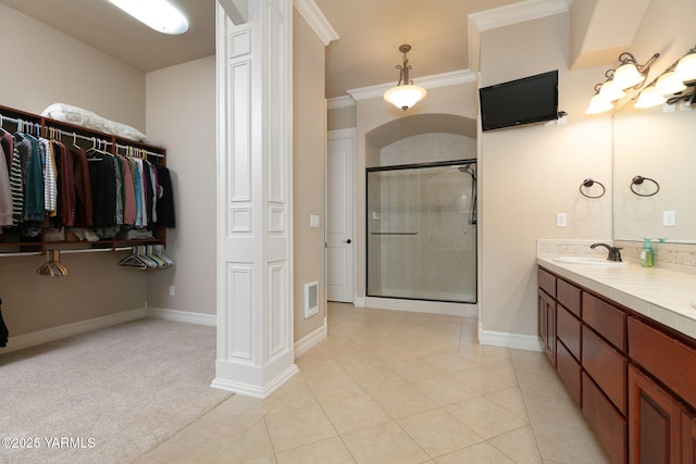 full bath featuring baseboards, double vanity, a stall shower, crown molding, and a sink