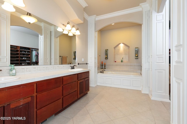 full bath with tile patterned floors, double vanity, a garden tub, and a sink