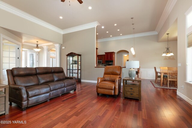 living area featuring ceiling fan, arched walkways, ornamental molding, recessed lighting, and dark wood-style flooring