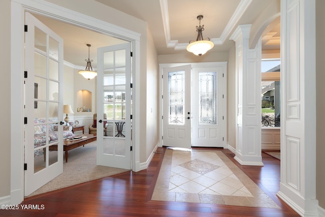 entryway featuring dark wood-type flooring, decorative columns, ornamental molding, and plenty of natural light