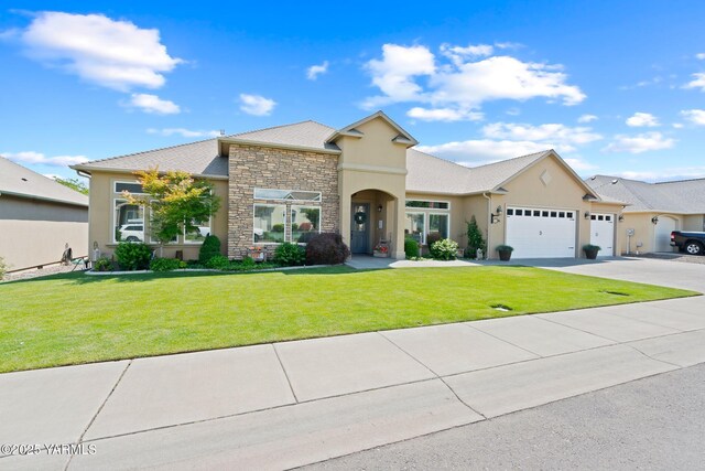 7506 Lyons Ln, Yakima, WA 98903 - view of front of house with an attached garage, stucco siding, a front lawn, stone siding, and concrete driveway