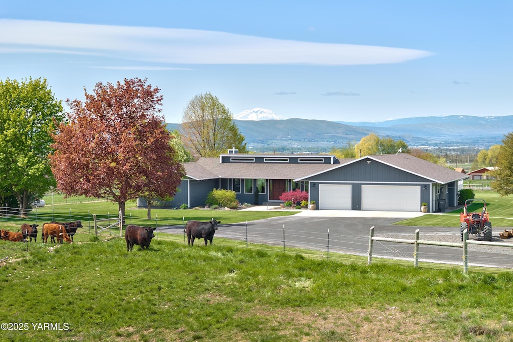 ranch-style house with concrete driveway, a mountain view, fence, and a garage