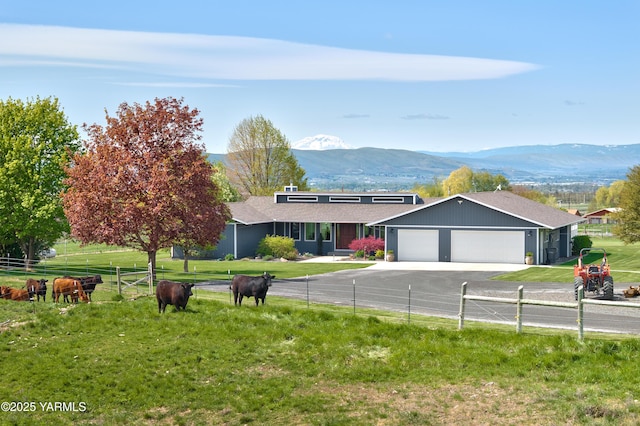 ranch-style house with concrete driveway, a mountain view, fence, and a garage