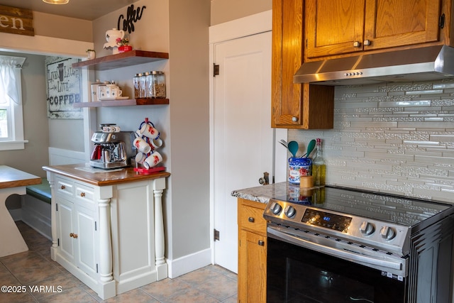 175001 W King Tull Rd, Grandview, WA 98930 - kitchen featuring stainless steel electric range oven, under cabinet range hood, light tile patterned flooring, baseboards, and tasteful backsplash