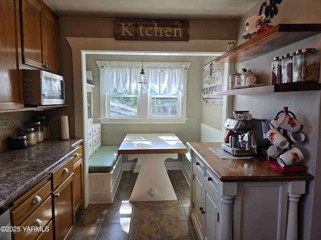 175001 W King Tull Rd, Grandview, WA 98930 - kitchen featuring stainless steel microwave, backsplash, brown cabinets, and open shelves