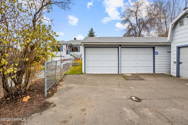 view of front of house featuring roof with shingles, a detached garage, and fence