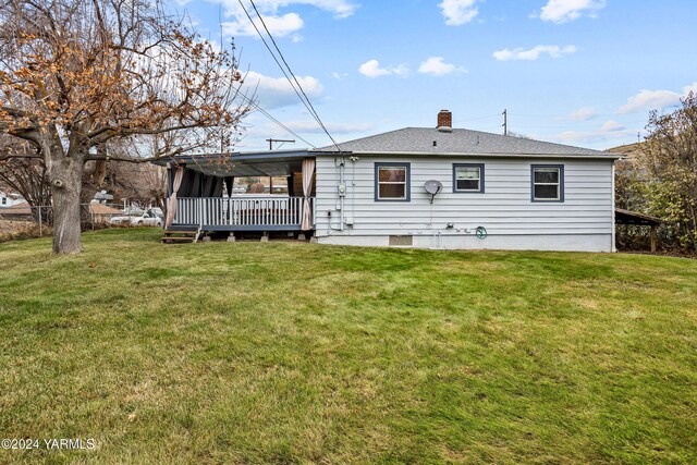 back of property featuring a chimney, a lawn, and roof with shingles