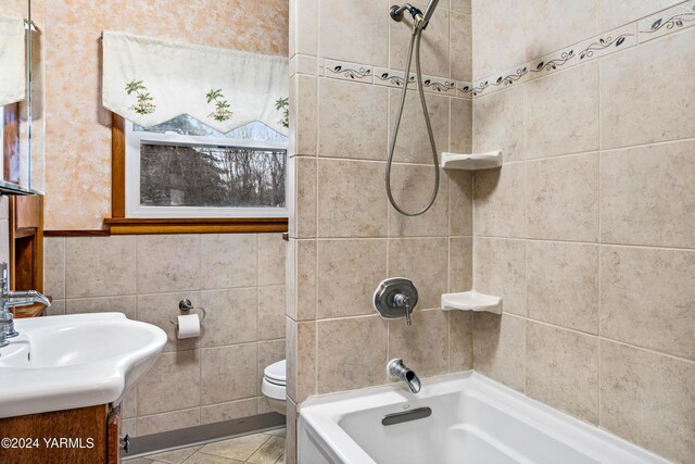 bathroom with tile patterned flooring, toilet, shower / tub combination, vanity, and tile walls