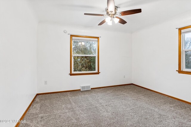 unfurnished room featuring baseboards, visible vents, plenty of natural light, and carpet flooring