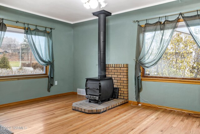 interior details with visible vents, baseboards, wood finished floors, a wood stove, and crown molding