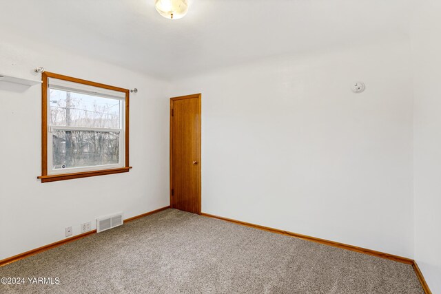 carpeted spare room featuring baseboards and visible vents