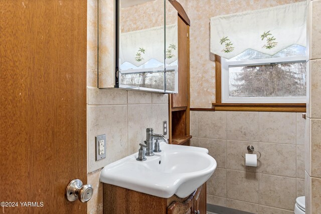 half bathroom featuring tile walls, vanity, and toilet