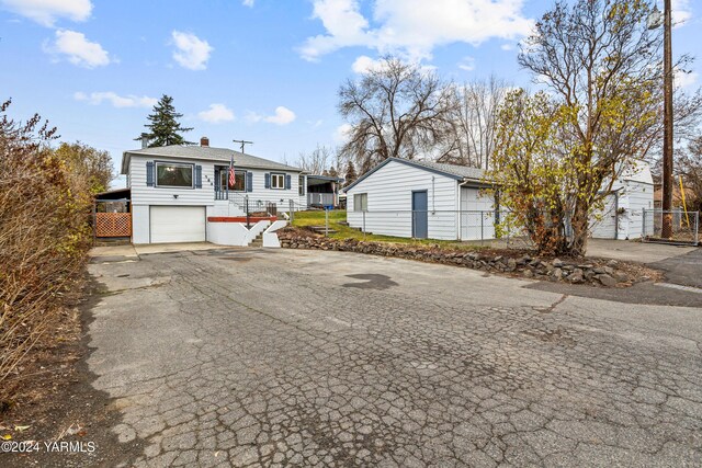 view of front of property featuring driveway, an attached garage, and fence