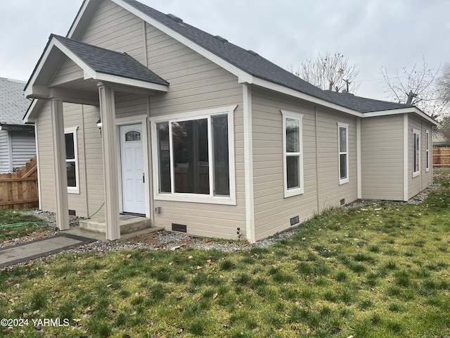 back of property with a shingled roof, crawl space, a lawn, and fence