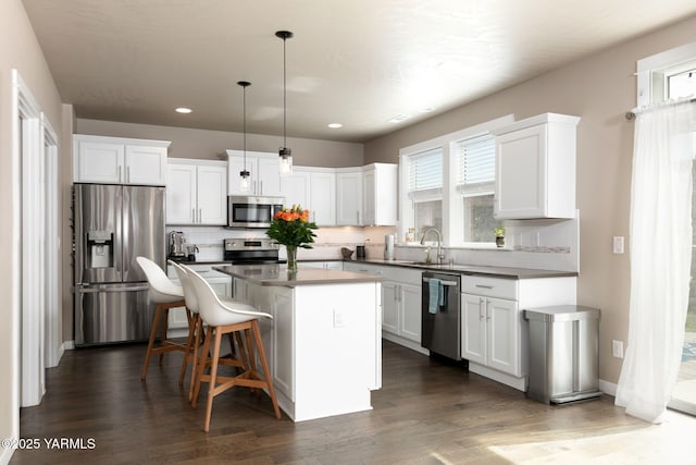 7902 W Whatcom Ave, Yakima, WA 98903 - kitchen with a kitchen island, white cabinets, a sink, appliances with stainless steel finishes, and backsplash
