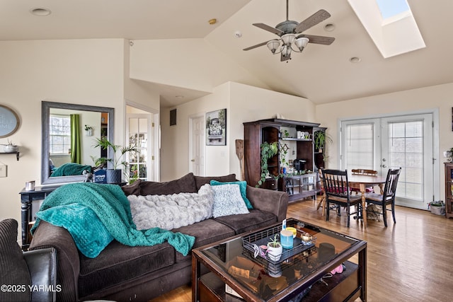 living area featuring a ceiling fan, a skylight, light wood-style flooring, and a wealth of natural light