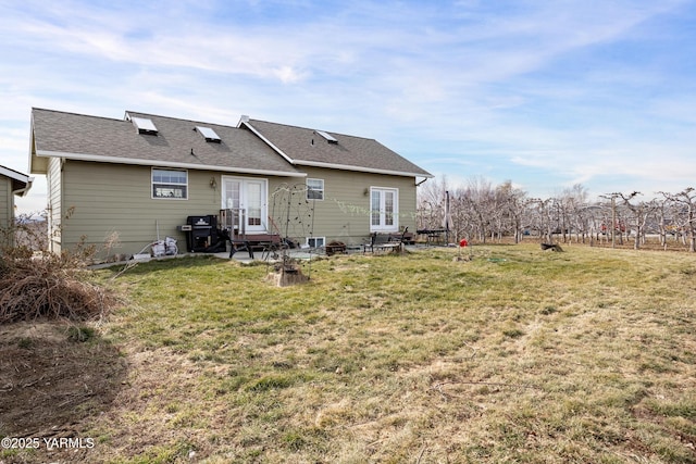 back of house featuring french doors, a lawn, and roof with shingles