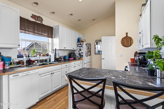 kitchen featuring white appliances, white cabinets, and dark countertops